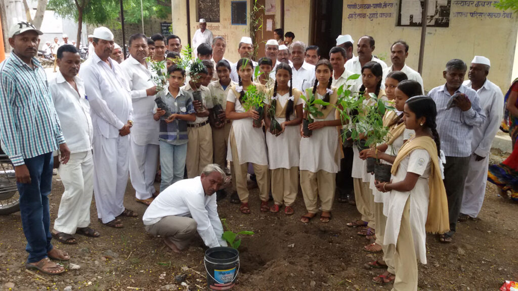 Students and villagers holding saplings at a Jai Hanuman Sanstha tree plantation drive in Hirapur, Nashik